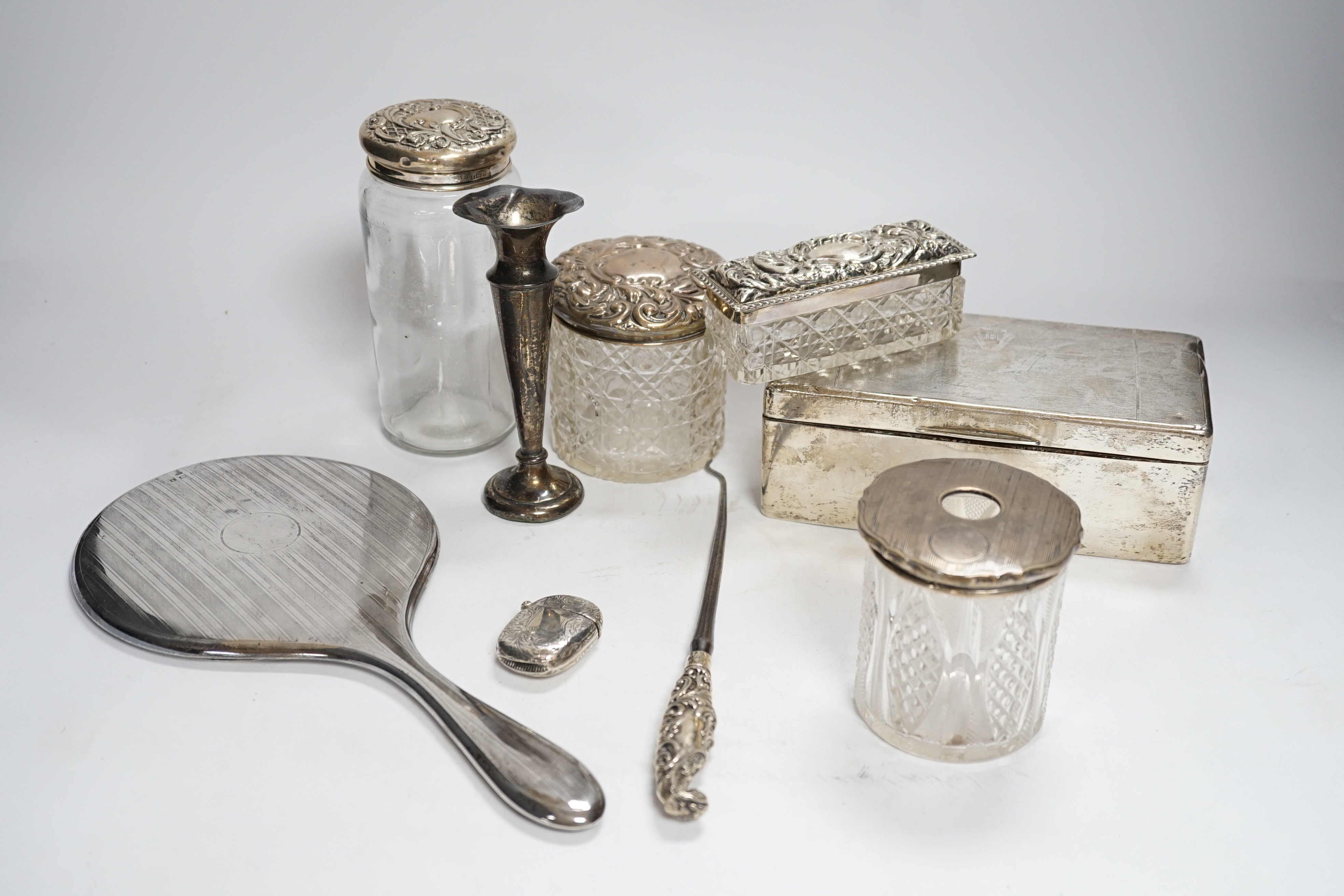Sundry small silver including a silver mounted cigarette box, four assorted mounted glass toilet jars, a vesta case, button hook, hand mirror and trumpet vase.